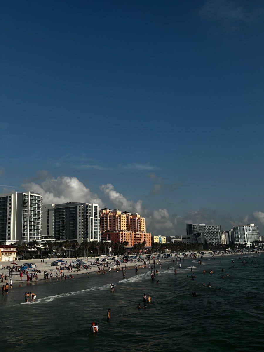 Beautiful sunny day at Clearwater Beach with high-rise buildings and a crowded shoreline.
